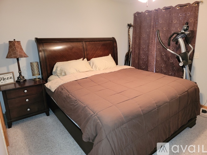 A bedroom with a large bed and a lamp on a nightstand.