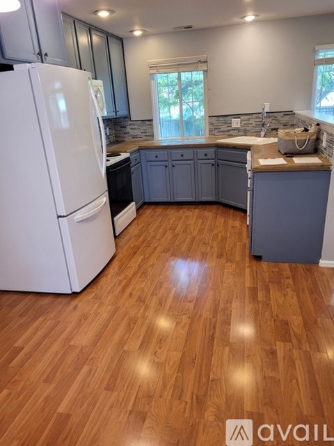 A kitchen with a white refrigerator and wooden floors.