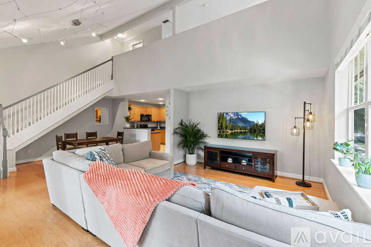 A living room with a grey couch and a television on the wall.