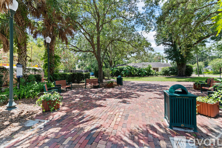 A park with a red brick walkway and green trees.