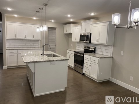 A kitchen with white cabinets and a granite countertop.
