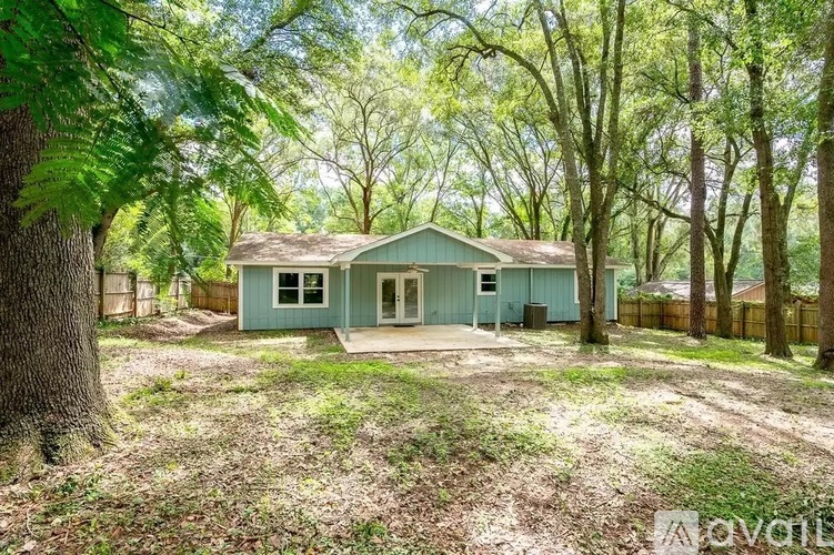 A small house is surrounded by trees and grass.