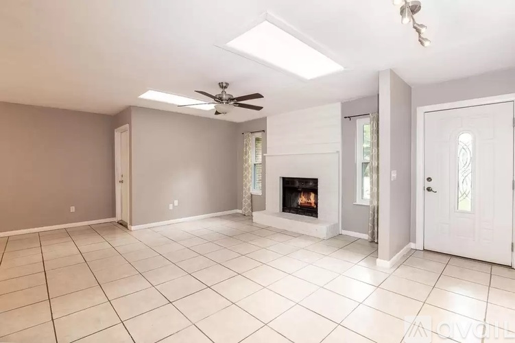 A spacious living room with a fireplace and a ceiling fan.