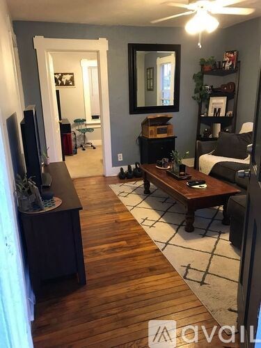 A living room with a wooden floor and a television on a stand.