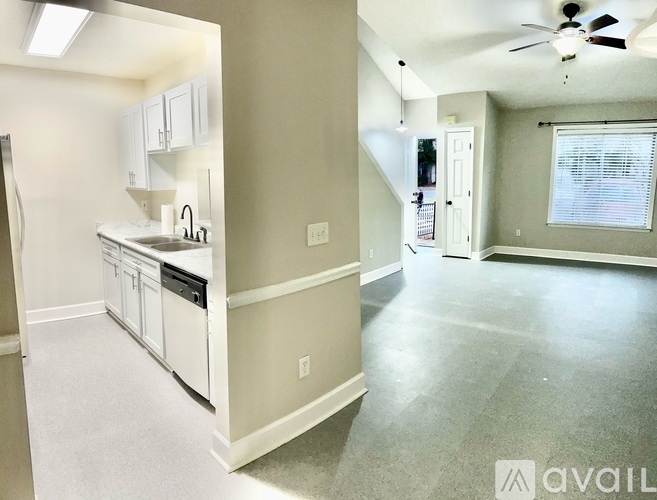 A spacious kitchen and living room with a ceiling fan and a window.