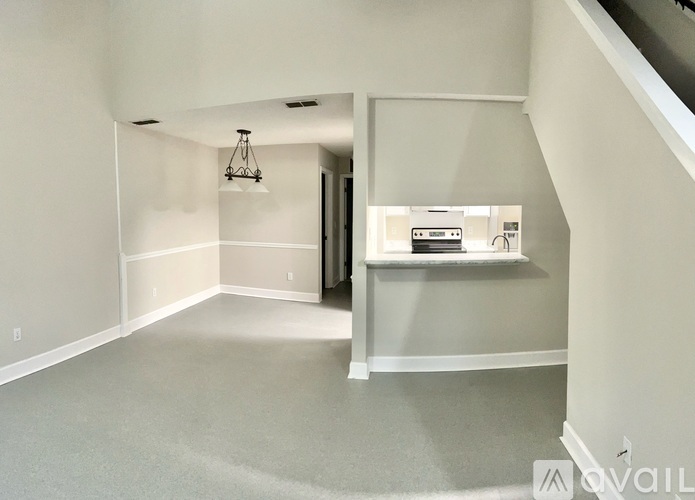A spacious room with a chandelier and a staircase.