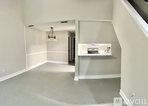 A spacious room with a chandelier and a staircase.