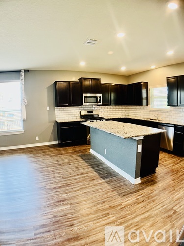 A kitchen with black cabinets and a wooden floor.