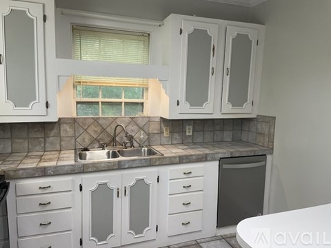 A kitchen with white cabinets and a marble countertop.
