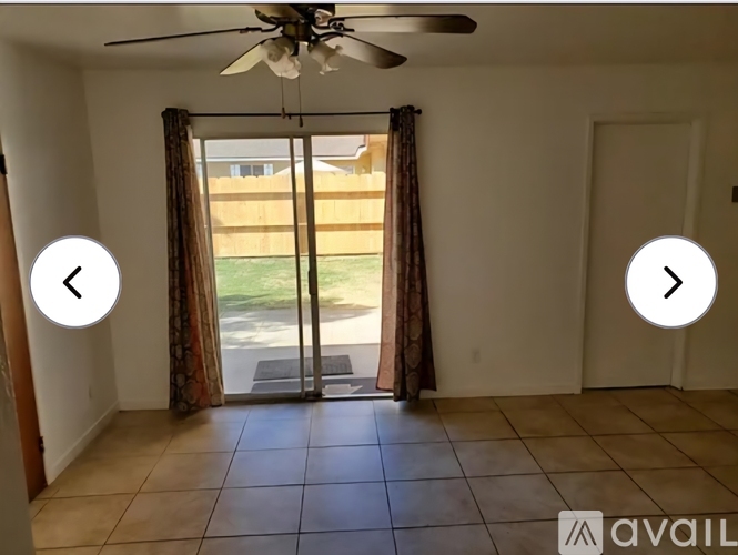 A room with a ceiling fan and sliding glass doors.