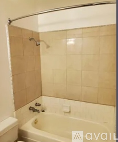A bathroom with a white tub and beige tiles.