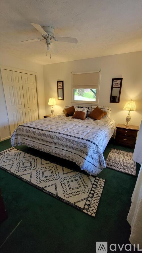 A bedroom with a bed, two lamps, and a rug.