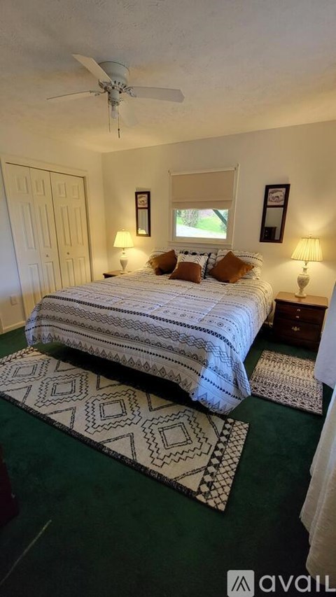 A bedroom with a bed, two lamps, and a rug.