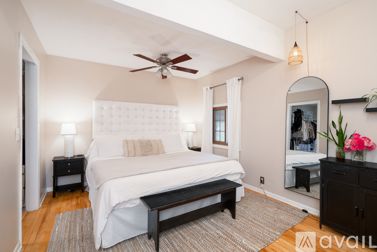 A bedroom with a large bed, a ceiling fan, and a mirror on the wall.