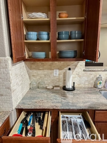 A kitchen counter with a sink and a cabinet with plates and bowls.