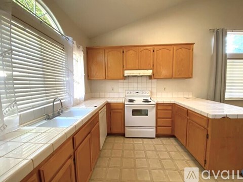 A kitchen with wooden cabinets and a white stove top oven.