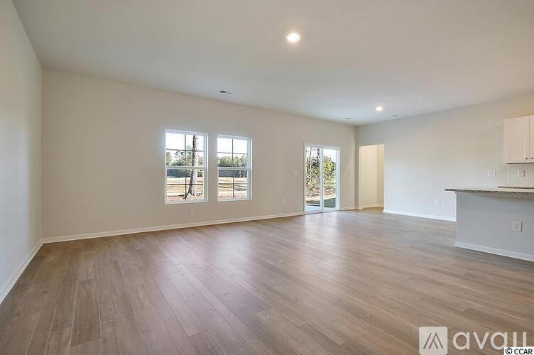 A spacious room with wooden flooring and a large window.