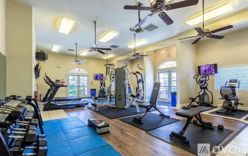 A well-equipped gym with various exercise machines and a TV screen.
