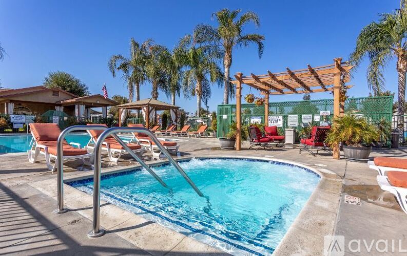 A pool area with a clear blue sky above and a wooden pergola in the background.