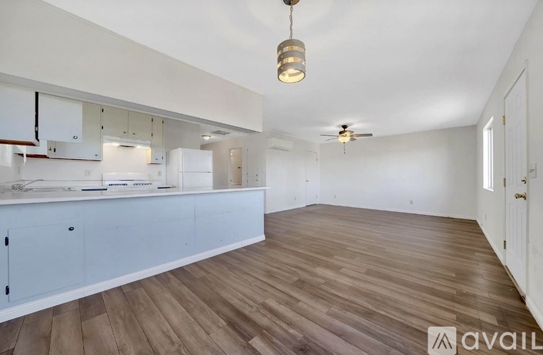 A kitchen with white cabinets and a wooden floor.