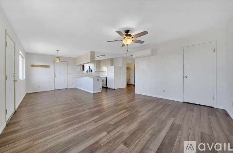 A spacious room with wooden flooring and a ceiling fan.
