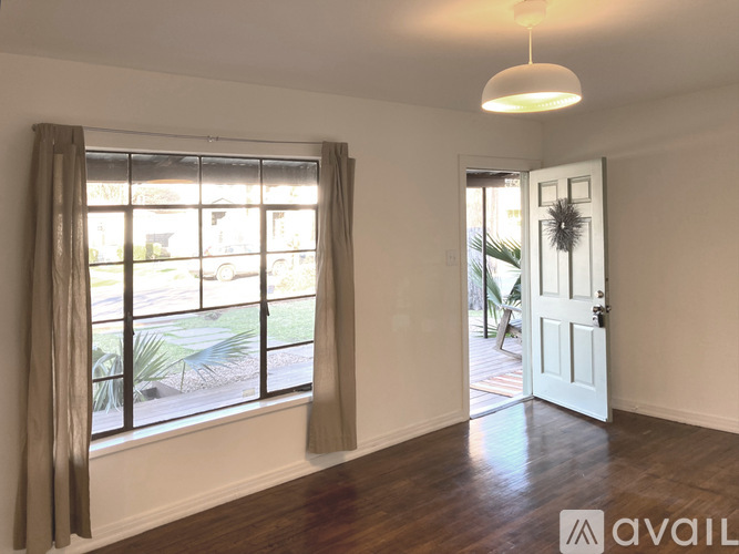 A room with a large window and a door leading to a balcony.