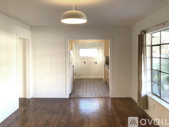 A spacious room with wooden floors and white walls.