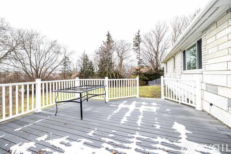 A table tennis table is on a deck with snow on the ground.