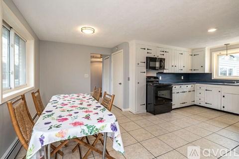 A kitchen with a table set for four with a floral tablecloth.