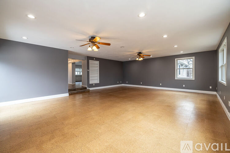 A spacious room with a ceiling fan and lighting fixtures.