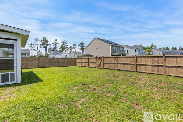 A grassy backyard with a wooden fence and houses in the background.
