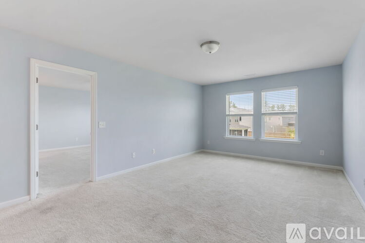 A spacious room with a carpeted floor and a door leading to another room.