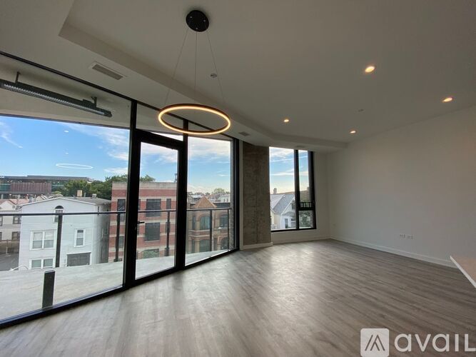 A spacious room with large windows and a wooden floor.