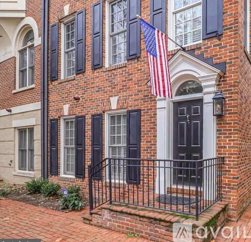A brick house with a black iron fence and an American flag.