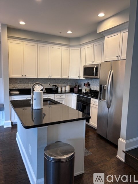 A kitchen with white cabinets and a black countertop.