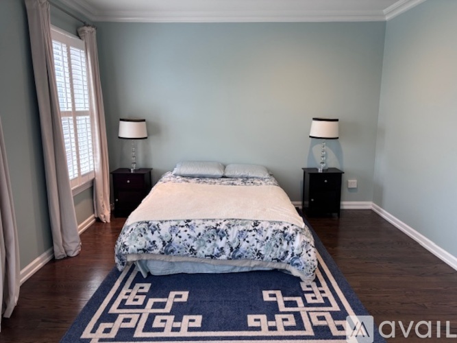A bedroom with a bed, two lamps, and a window with curtains.
