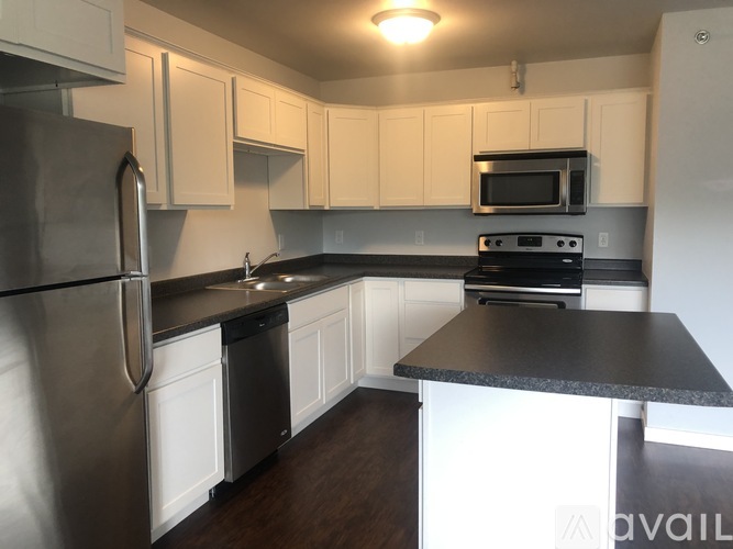 A kitchen with white cabinets and a black countertop.