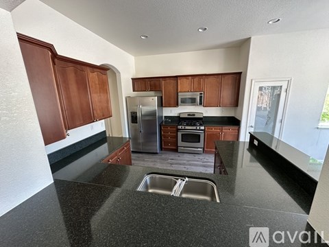 A kitchen with brown cabinets and a black countertop.