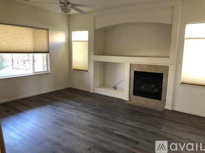 A living room with a fireplace and a ceiling fan.