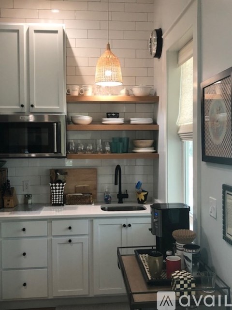 A kitchen with white cabinets and a black microwave.