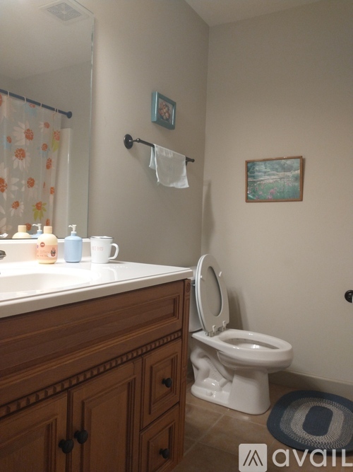 A white toilet is in a bathroom with a wooden vanity and a picture frame on the wall.