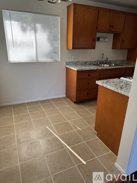 A kitchen with wooden cabinets and a marble countertop.