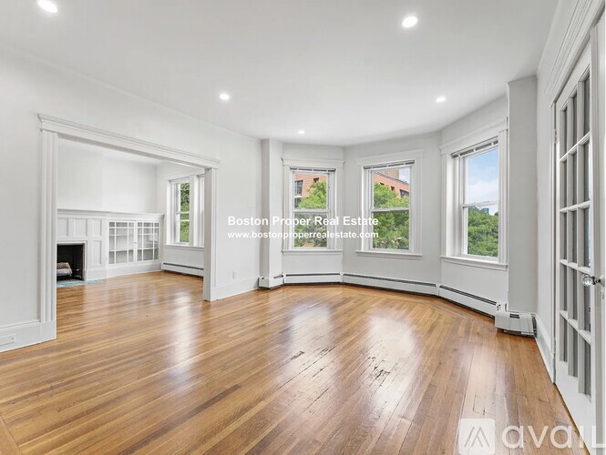 A spacious room with wooden floors and white walls.