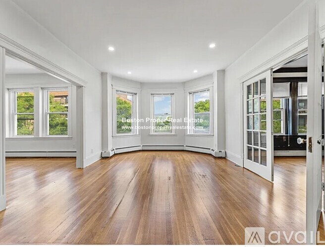 A spacious room with wooden floors and large windows.