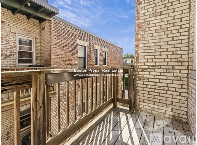 A balcony with a wooden railing and brick walls.