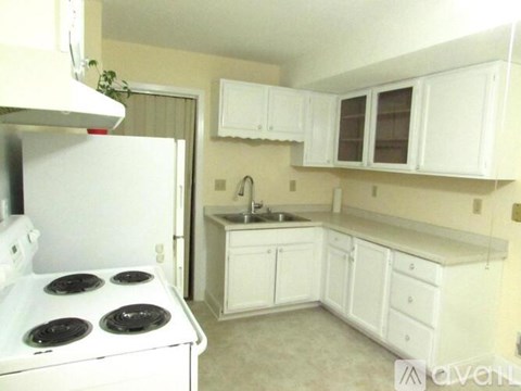 A small kitchen with a white stove and cabinets.