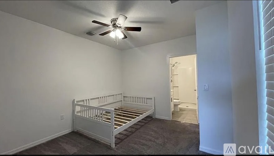 A bedroom with a white bed and a ceiling fan.