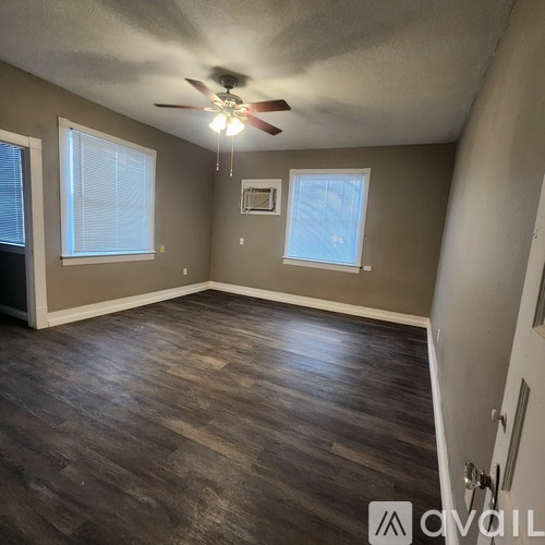 A room with a ceiling fan and wooden flooring.