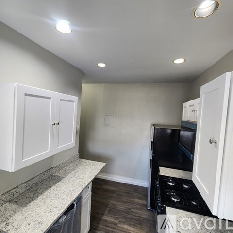 A kitchen with white cabinets and a granite countertop.