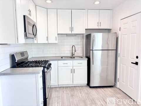 A kitchen with white cabinets and a stainless steel refrigerator.